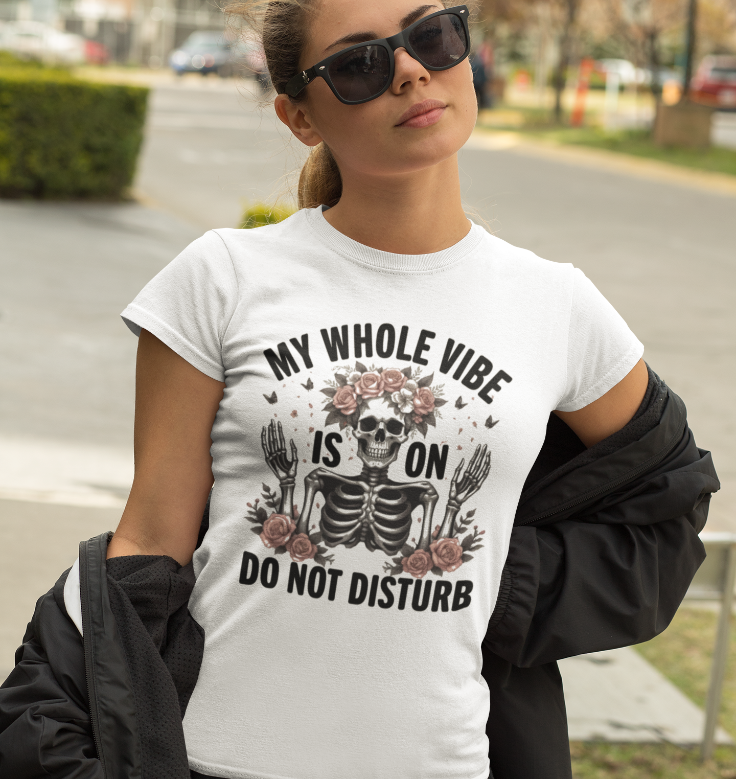 Γυναίκα με γυαλιά ηλίου φοράει λευκό t-shirt με σχέδιο σκελετού και τριαντάφυλλα και τη φράση “My Whole Vibe is On – Do Not Disturb”.