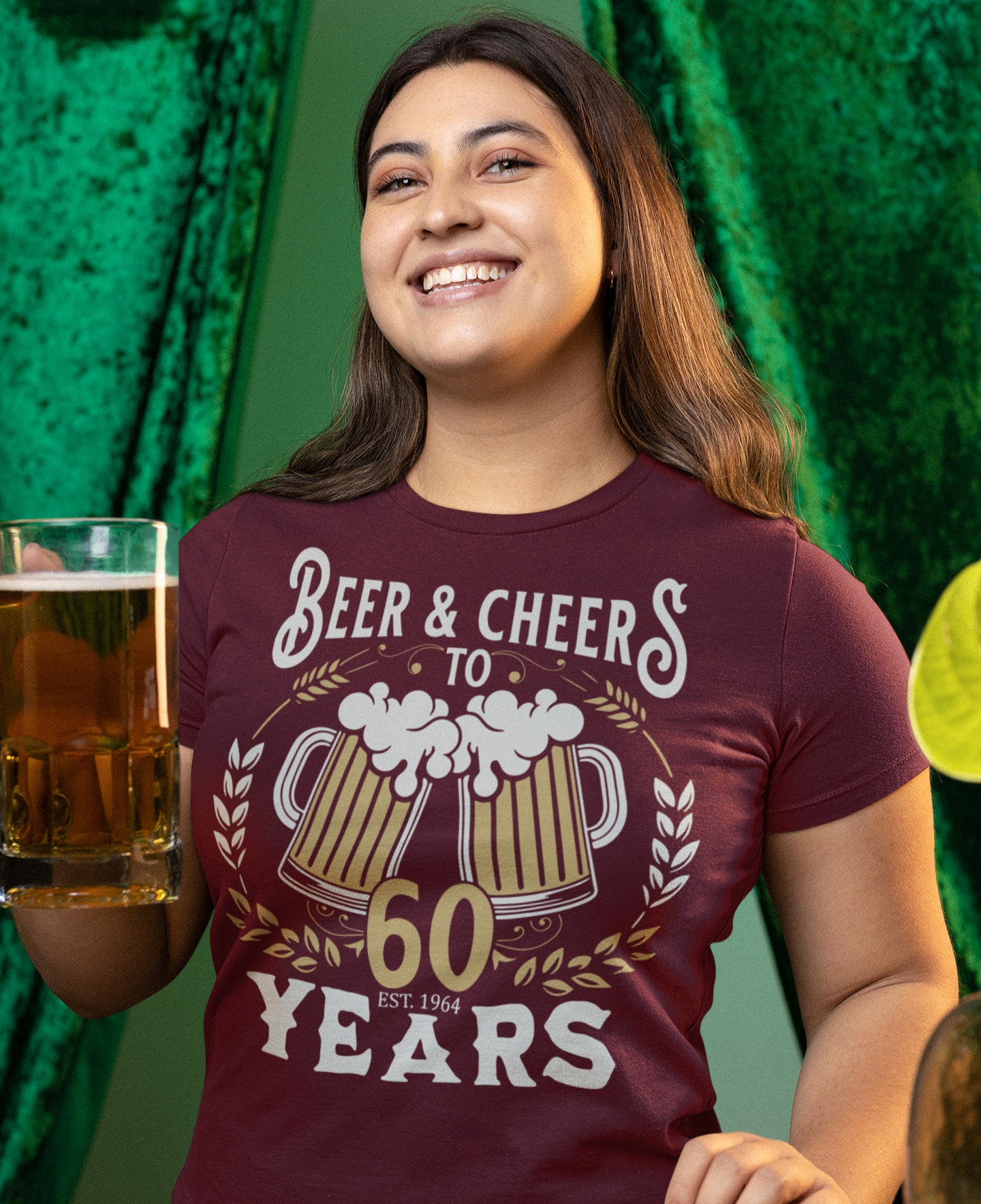 Χαμογελαστή γυναίκα κρατάει ποτήρι μπύρας και φοράει μπλουζάκι με σχέδιο "Beer & Cheers to 60 Years" με δύο κούπες μπύρας και ημερομηνία 1964.