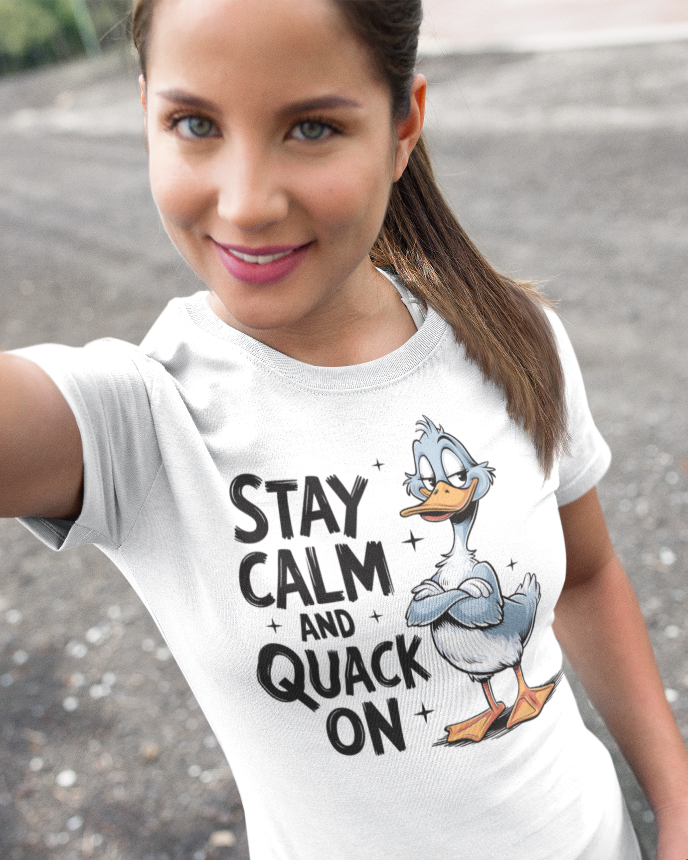 Γυναίκα φοράει λευκό t-shirt με τύπωμα "Stay Calm and Quack On" και σχέδιο πάπιας, selfie σε εξωτερικό χώρο