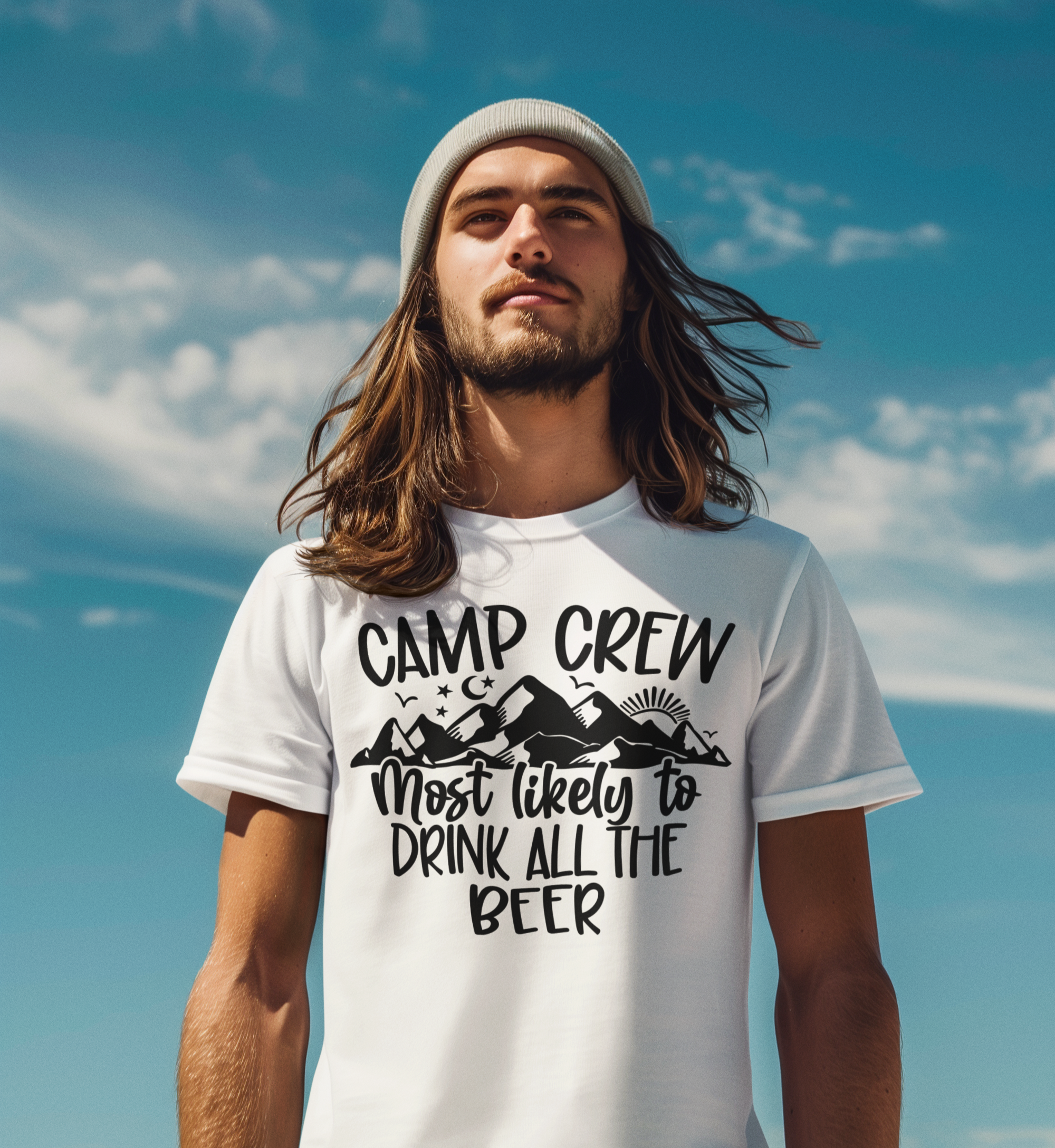 Άνδρας με μακριά μαλλιά και σκούφο ποζάρει με λευκό t-shirt “Camp Crew – Most Likely to Drink All the Beer” κάτω από γαλανό ουρανό.