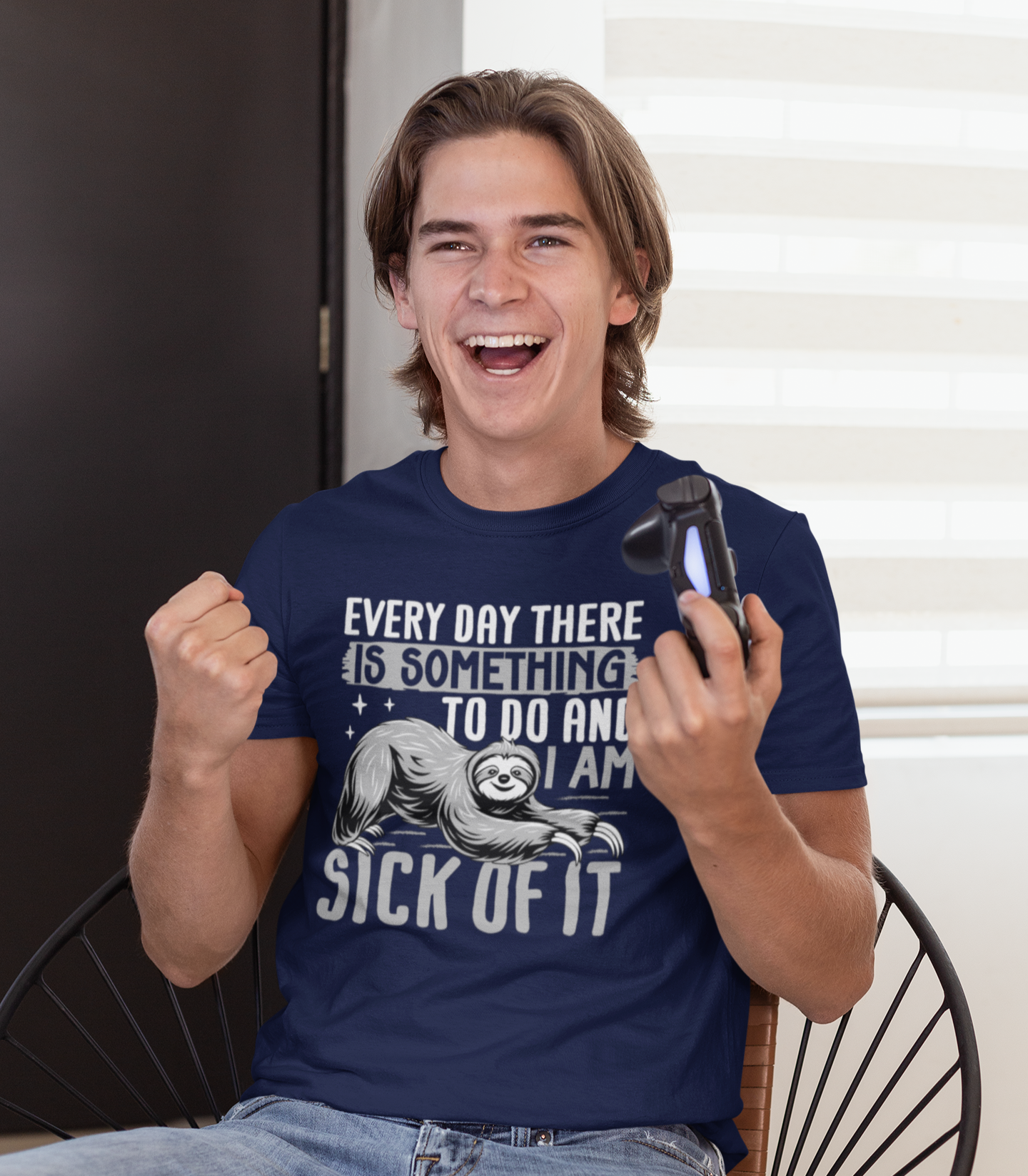 Χαμογελαστός νεαρός με μπλε μπλουζάκι που γράφει “Every day there is something to do and I am sick of it” και κρατάει χειριστήριο PlayStation