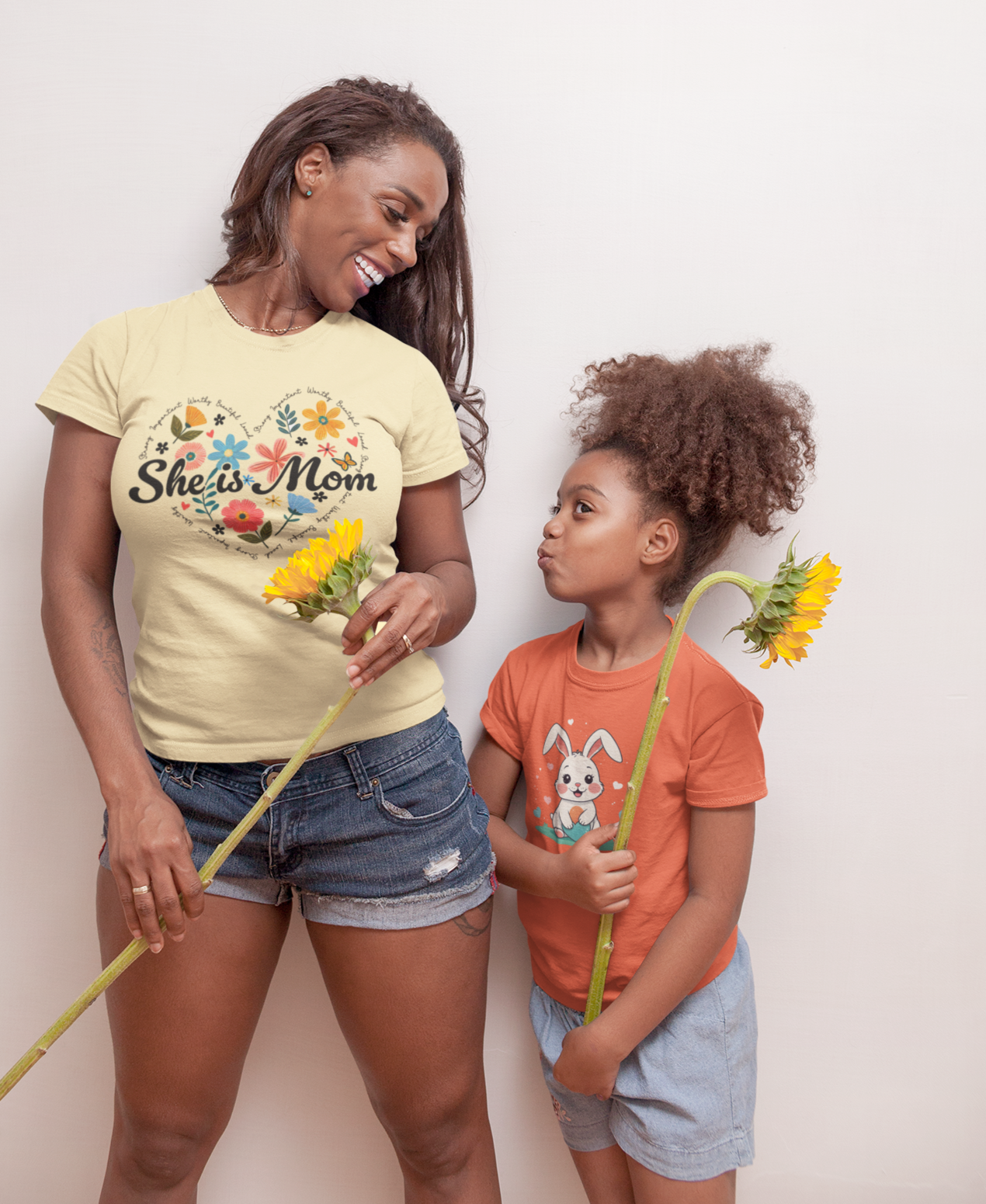 μπλουζάκια με σχέδιο She is Mom και κουνελάκι, μπροστά από λευκό φόντο.