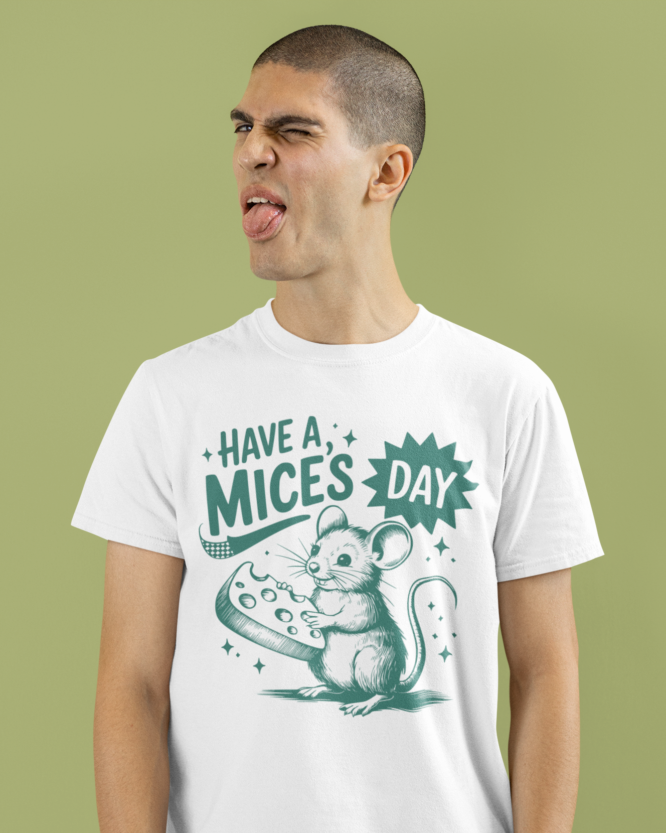 Άντρας με λευκό μπλουζάκι "Have a Mice’s Day" με ποντίκι και τυρί, κάνει αστεία γκριμάτσα μπροστά σε πράσινο φόντο.