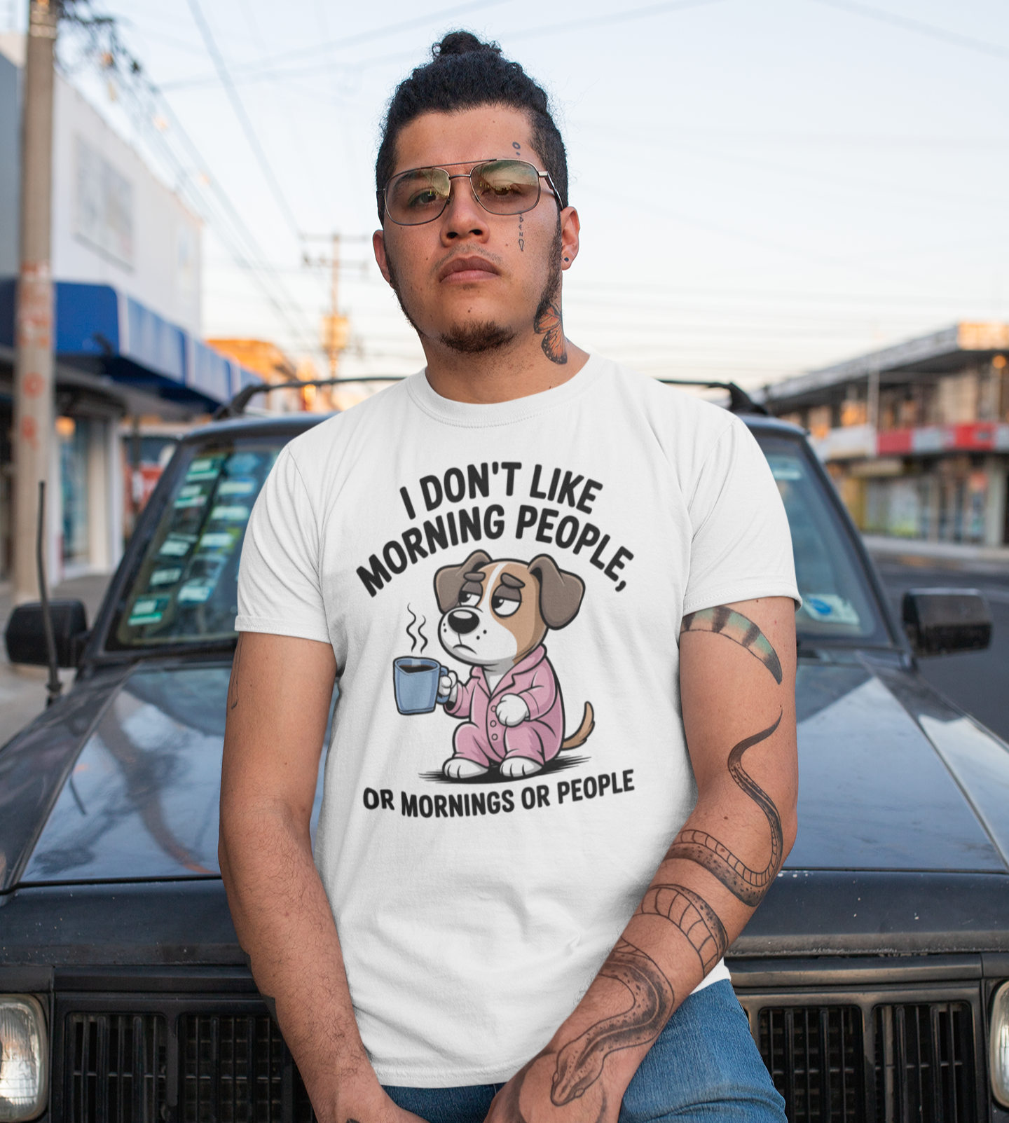 Άντρας με τατουάζ φοράει αστείο λευκό t-shirt με σκυλάκι που κρατάει καφέ και τη φράση “I don’t like morning people – or mornings or people”.