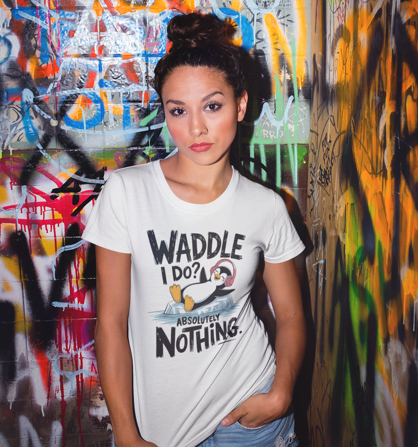 Γυναίκα μπροστά σε τοίχο με γκράφιτι φοράει t-shirt με πιγκουίνο και τη φράση "Waddle I Do? Absolutely Nothing"