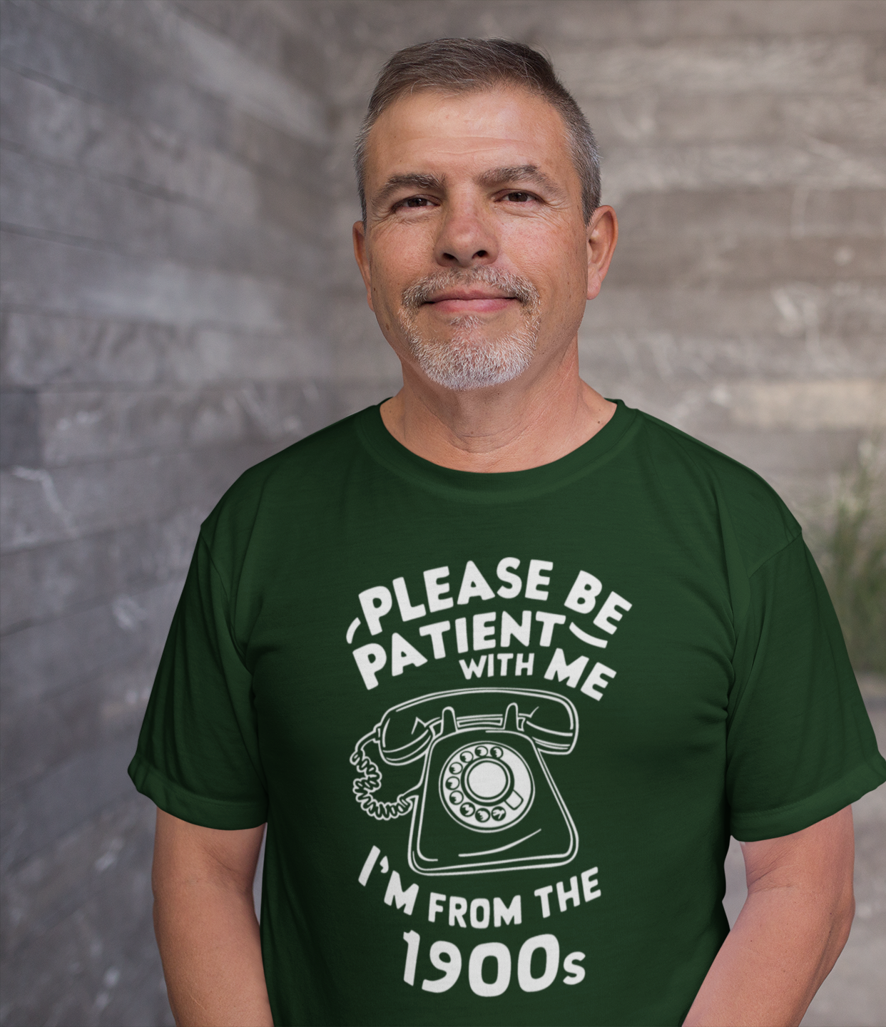 Μεσήλικας άνδρας χαμογελάει φορώντας μπλουζάκι με ρετρό τηλέφωνο και το κείμενο “Please be patient with me – I’m from the 1900s”.