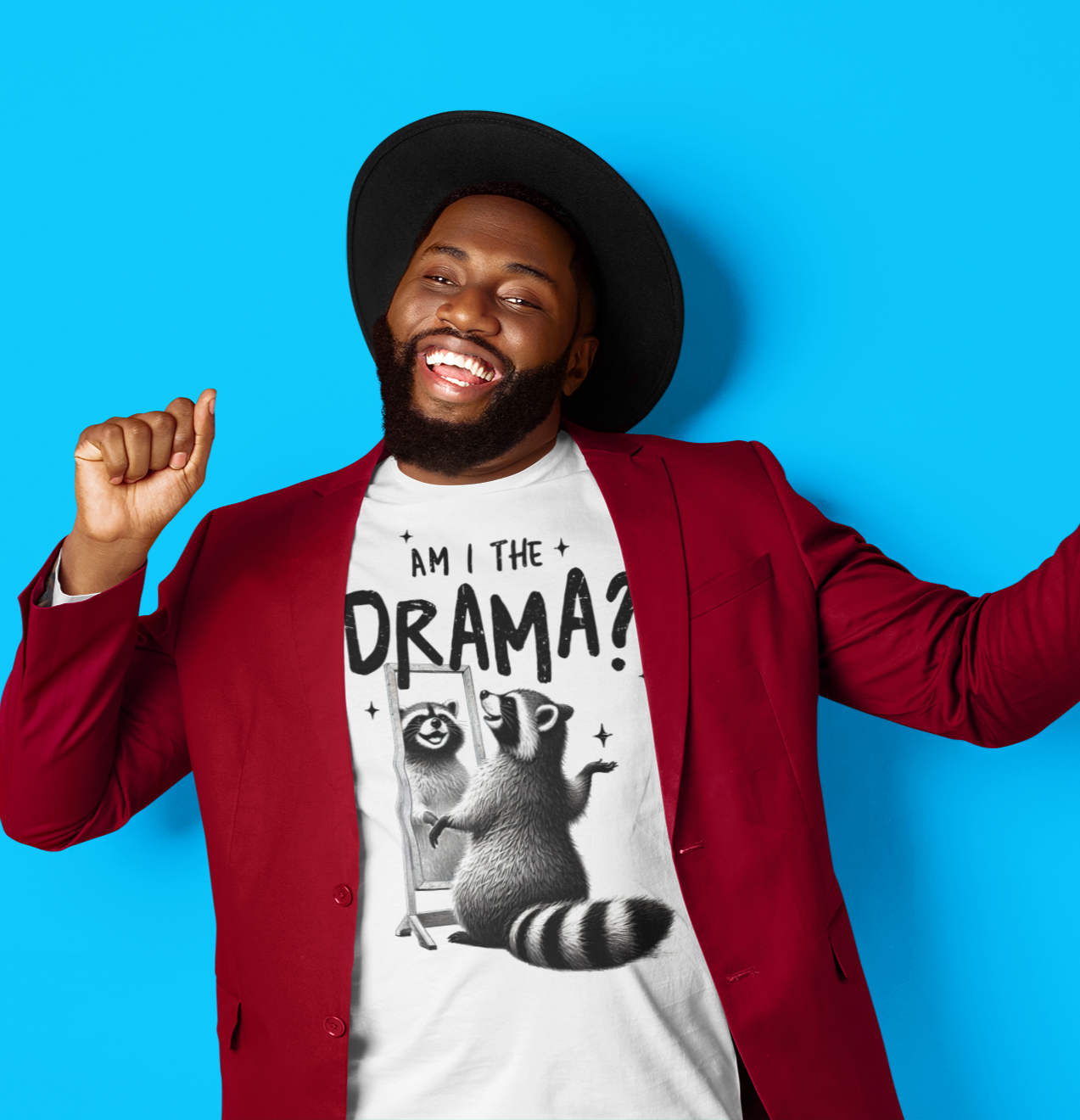 Χαμογελαστός άνδρας με καπέλο και μπορντό σακάκι χορεύει φορώντας λευκό t-shirt με τη φράση "Am I the Drama?" και ένα ρακούν μπροστά σε καθρέφτη.